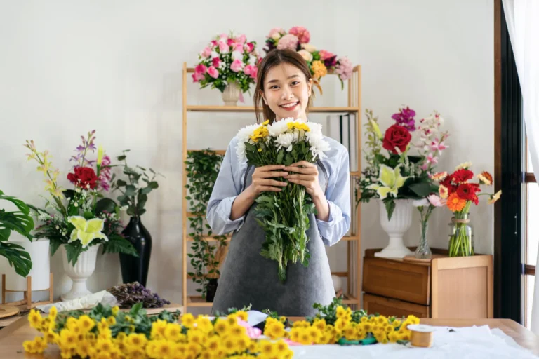 female florist apron smiling holding chrysanthemum with e Horizontal 768x512